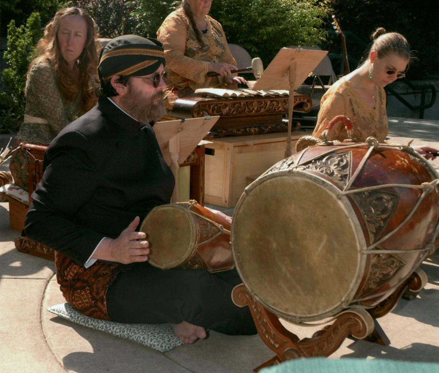 A man plays the drums with the rest of the ensemble behind him