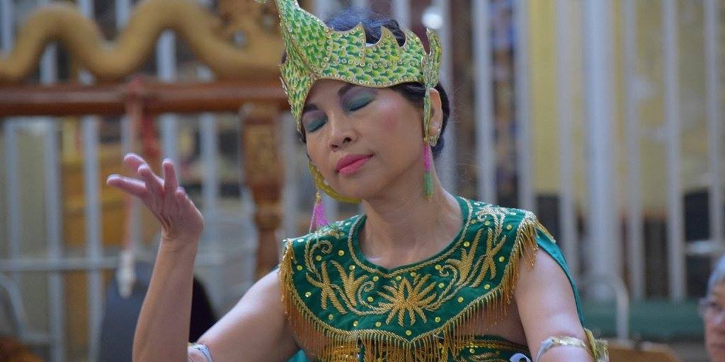 An ornately-dressed dancer in green and gold pensively posing
